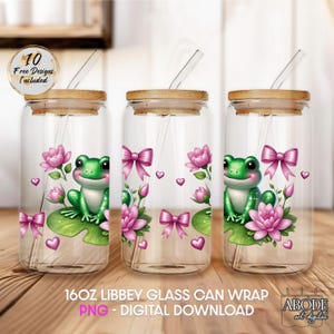 Peut inclure: Trois gobelets en verre transparent en forme de canette avec des couvercles et des pailles en bambou. Chaque gobelet présente une grenouille de dessin animé sur un nénuphar, des nœuds roses et des fleurs. Le texte "16OZ LIBBEY GLASS CAN WRAP" est visible.