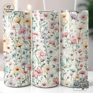 Könnte beinhalten: Drei Trinkbecher mit Blumenmuster auf weißem Hintergrund. Das Design ist im Aquarellstil gehalten und zeigt verschiedene Blumen in Pastellfarben, darunter Rosa, Gelb, Blau und Lila. Die Becher haben einen Strohhalm und den Text "10 Free Designs Included".