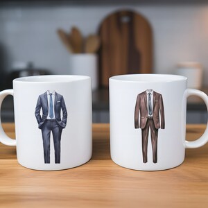 以下が含まれることがあります： スーツのデザインが施された白いセラミック製のマグカップ2つ。1つのマグカップには青いスーツ、もう1つのマグカップには茶色のスーツが描かれています。