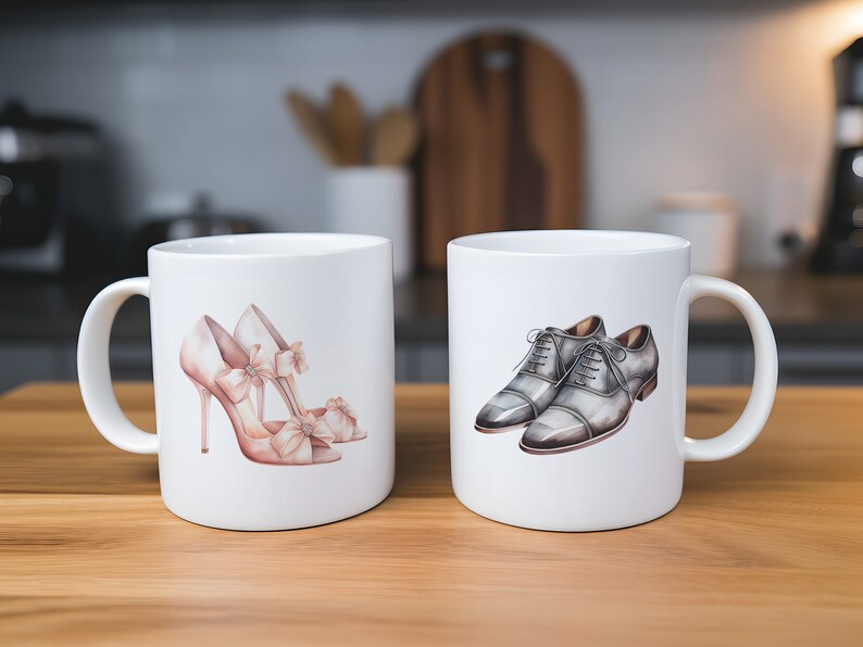May include: Two white ceramic mugs, each with a shoe design. One has pink high heels with bows, the other features grey dress shoes. The mugs are on a wooden surface, with a blurred kitchen background.