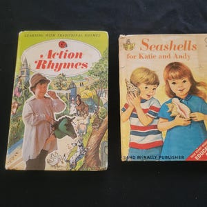 May include: Two vintage children's books. The book on the left is titled "Action Rhymes" with a boy on the cover. The book on the right is titled "Seashells for Katie and Andy" with two children holding seashells. Both books have colorful illustrations.