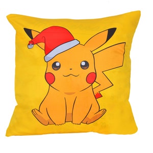 May include: Yellow throw pillow with a cartoon image of Pikachu wearing a red and white Santa hat.