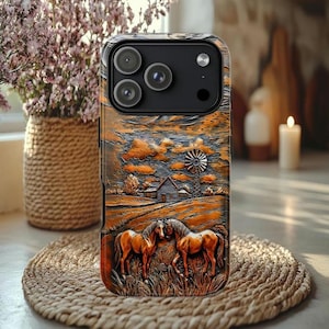 May include: A phone case with a detailed relief design featuring a rural landscape with two horses, a farmhouse, and a windmill. The case has a brown and orange color scheme, with a textured appearance.
