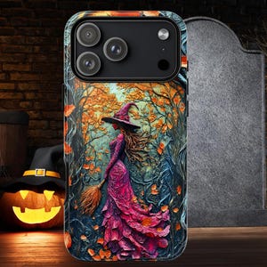 Puede incluir: Una funda de teléfono con una bruja con un vestido y sombrero rosas, sosteniendo una escoba, caminando por un bosque con hojas naranjas. Una calabaza tallada y un sombrero de bruja están en el fondo, con una lápida a la derecha.