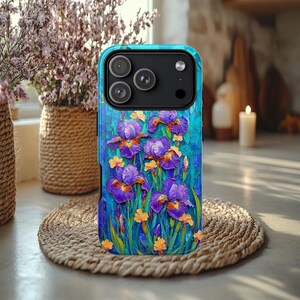 May include: A teal phone case featuring a vibrant floral design of purple irises with orange and yellow accents. The case has a textured, artistic appearance, with a black camera module at the top.