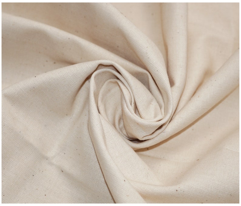 May include: Close-up of a natural off-white fabric with a slightly textured surface. The fabric is folded and draped, showcasing its soft and drapey quality.