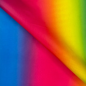 May include: A vibrant rainbow-colored fabric with a grid pattern. The colors transition smoothly from blue to red, then to yellow and green. The fabric is folded over, revealing the underside and adding depth to the image.
