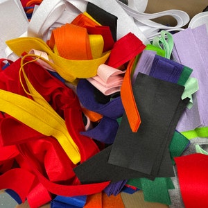 K&ouml;nnte beinhalten: Eine Vielzahl von Filzstoffresten in verschiedenen Farben, darunter Rot, Orange, Gelb, Gr&uuml;n, Blau, Lila und Wei&szlig;. Der Filz ist zu einem Stapel angeordnet, wobei sich einige St&uuml;cke &uuml;berlappen.