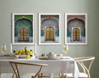 Op de afbeelding: Drie ingelijste prints van sierlijke deuren met ingewikkelde tegelwerk en gebogen doorgangen. De deuren zijn geschilderd in tinten groen, blauw en goud. De prints hangen aan een lichtgroene muur.