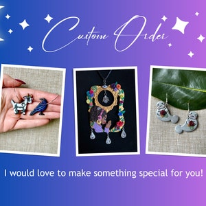 May include: Three handmade polymer clay jewelry pieces: a necklace with a black crow and a white goat charm, a necklace with a framed portrait of a woman with a crown of flowers, and a pair of earrings with a gray seal holding a red rose.