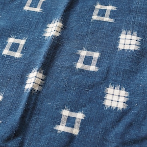 Könnte beinhalten: Nahaufnahme eines blauen Stoffes mit einem weißen geometrischen Muster. Das Muster besteht aus kleinen Quadraten mit einem karierten Design.