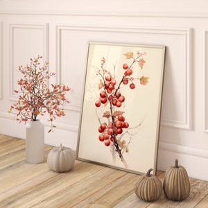 May include: A framed watercolor painting of a branch with red berries and green leaves. The painting is hanging on a white wall with a white wainscoting trim. There are two small decorative pumpkins on the floor in front of the painting.