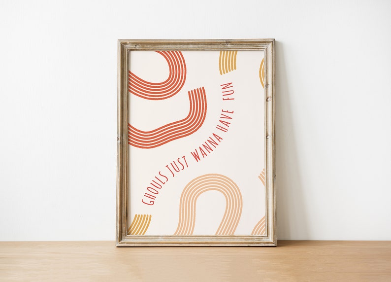May include: A framed print with a white background and red and yellow abstract shapes. The text "Ghouls just wanna have fun" is written in red.