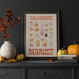 Puede incluir: Una impresi&oacute;n enmarcada con el texto "Halloween Market" en una fuente retro. La impresi&oacute;n presenta una variedad de golosinas de Halloween lindas de estilo de dibujos animados, que incluyen calabazas, cupcakes y fantasmas, todos con caras sonrientes. La impresi&oacute;n se coloca sobre un fondo gris oscuro, con un jarr&oacute;n de hojas de oto&ntilde;o y calabazas en primer plano.