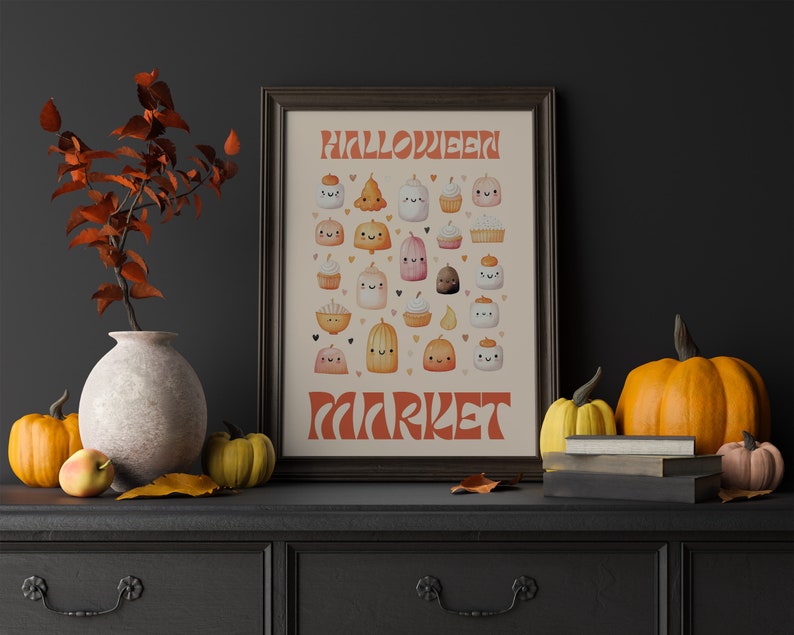 Puede incluir: Una impresi&oacute;n enmarcada con el texto "Halloween Market" en una fuente retro. La impresi&oacute;n presenta una variedad de golosinas de Halloween lindas de estilo de dibujos animados, que incluyen calabazas, cupcakes y fantasmas, todos con caras sonrientes. La impresi&oacute;n se coloca sobre un fondo gris oscuro, con un jarr&oacute;n de hojas de oto&ntilde;o y calabazas en primer plano.