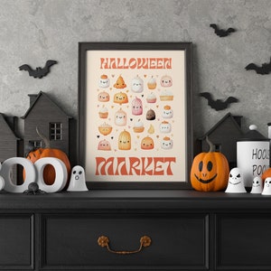 Puede incluir: Una impresi&oacute;n enmarcada en negro con el texto "Halloween Market" en letras naranja y blancas. La impresi&oacute;n presenta una variedad de golosinas lindas con tem&aacute;tica de Halloween, que incluyen calabazas, fantasmas y cupcakes. La impresi&oacute;n se muestra en una c&oacute;moda negra con un letrero blanco BOO, dos ara&ntilde;as negras, dos fantasmas blancos y dos calabazas naranjas.