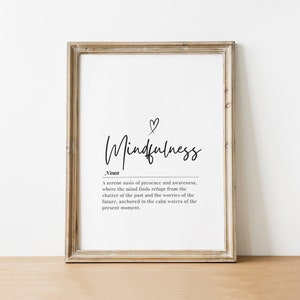 May include: A black and white printable wall art print with the word "Mindfulness" in cursive script and a definition of the word. The print is framed in a light brown wood frame.
