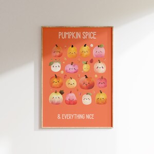 May include: A framed art print featuring a collection of smiling pumpkins in various colors, set against an orange background. The text "PUMPKIN SPICE & EVERYTHING NICE" is displayed in white. The artwork is in a wooden frame.