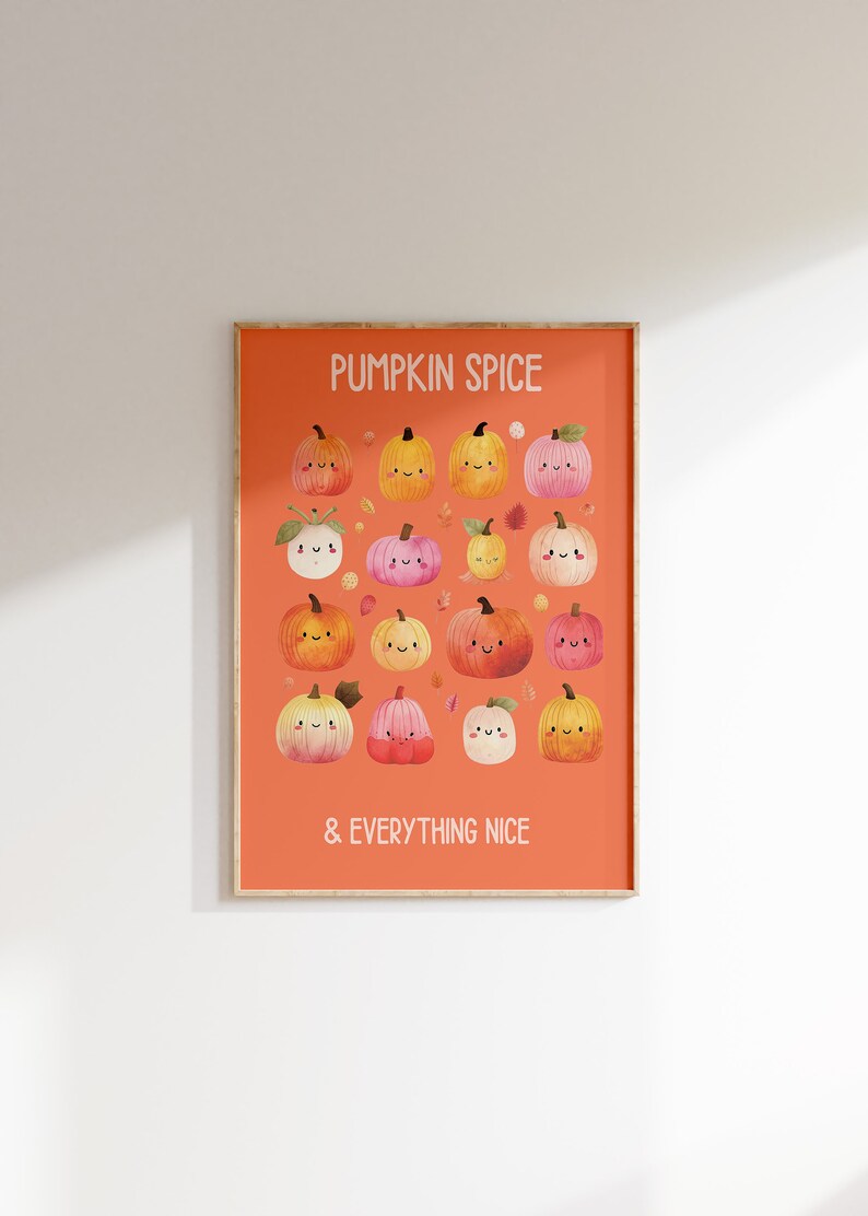 May include: A framed art print featuring a collection of smiling pumpkins in various colors, set against an orange background. The text "PUMPKIN SPICE & EVERYTHING NICE" is displayed in white. The artwork is in a wooden frame.