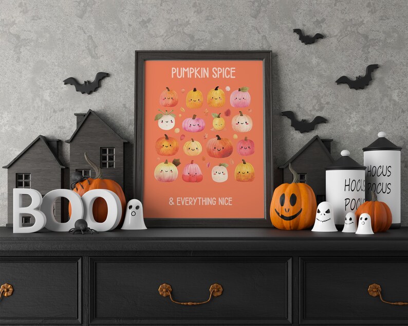 May include: A framed orange print with the text "PUMPKIN SPICE & EVERYTHING NICE" and illustrations of smiling pumpkins. The print is displayed on a black dresser with Halloween decorations, including pumpkins, ghosts, and bats.