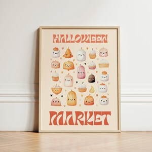May include: A framed print with a light orange background featuring the text "Halloween Market" in a retro font. The print is filled with cute cartoon images of pumpkins, ghosts, and cupcakes.