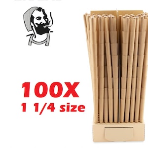 Può includere: Una scatola di 100 coni prerollati Zig-Zag di misura 1 1/4. I coni sono marroni e sono disposti in uno schema a griglia. La scatola è marrone e ha il logo Zig-Zag.