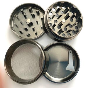 Puede incluir: Un molinillo de hierbas de metal negro de cuatro piezas mostrado desmontado. Las dos piezas superiores cuentan con dientes afilados en forma de diamante y un im&aacute;n central. Las dos piezas inferiores incluyen una malla met&aacute;lica fina y una c&aacute;mara de recolecci&oacute;n lisa con una peque&ntilde;a esp&aacute;tula de pl&aacute;stico blanco.