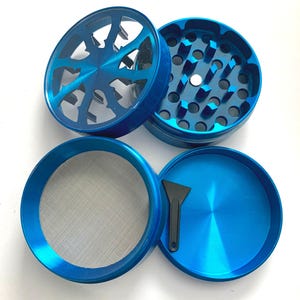 Puede incluir: Un molinillo de hierbas de metal azul de cuatro piezas con tapa transparente, dientes de trituraci&oacute;n afilados, una malla fina para tamizar y una peque&ntilde;a esp&aacute;tula de pl&aacute;stico negro. Los componentes est&aacute;n desmontados.