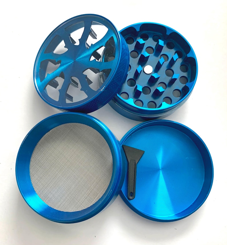 Puede incluir: Un molinillo de hierbas de metal azul de cuatro piezas con tapa transparente, dientes de trituraci&oacute;n afilados, una malla fina para tamizar y una peque&ntilde;a esp&aacute;tula de pl&aacute;stico negro. Los componentes est&aacute;n desmontados.