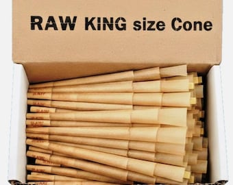 Puede incluir: Una caja de cartón que contiene una pila de conos de papel sin blanquear de color marrón claro. La solapa interior de la caja presenta el texto negro RAW KING size Cone. Cada cono es cónico e incluye una pequeña boquilla de papel clara.