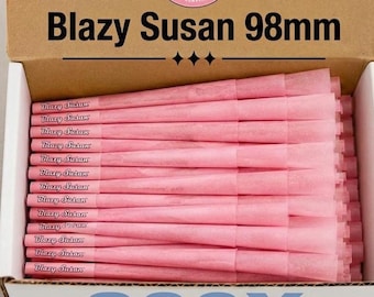 Puede incluir: Una caja de cartón que contiene una pila de conos preenrollados de color rosa, cada uno etiquetado con el texto Blazy Susan. La tapa de la caja muestra el texto Blazy Susan 98mm. Los conos están dispuestos horizontalmente en una fila ordenada.