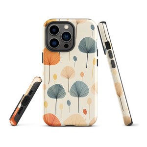 Puede incluir: Una funda para teléfono con fondo blanco y un patrón de hojas naranjas, azules y amarillas. La funda tiene una protuberancia de cámara negra con tres lentes.