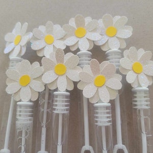 May include: A set of eight white daisy-shaped bubble wands with yellow centers. The wands are made of clear plastic and have a white handle.