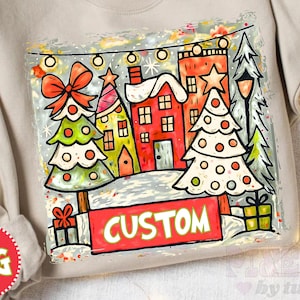 May include: A beige sweatshirt featuring a colorful Christmas scene. The design includes decorated trees, houses, and the word "CUSTOM" on a red banner. The graphic is outlined with a glittery border, creating a festive look.