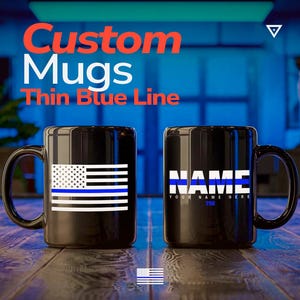 May include: Two black ceramic mugs featuring the text Custom Mugs Thin Blue Line. One mug displays a black and white American flag with a horizontal blue stripe. The other mug shows the word NAME with a blue stripe, followed by YOUR NAME HERE 756.
