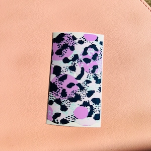 May include: A sticker featuring an abstract animal print design in pink, white and black.