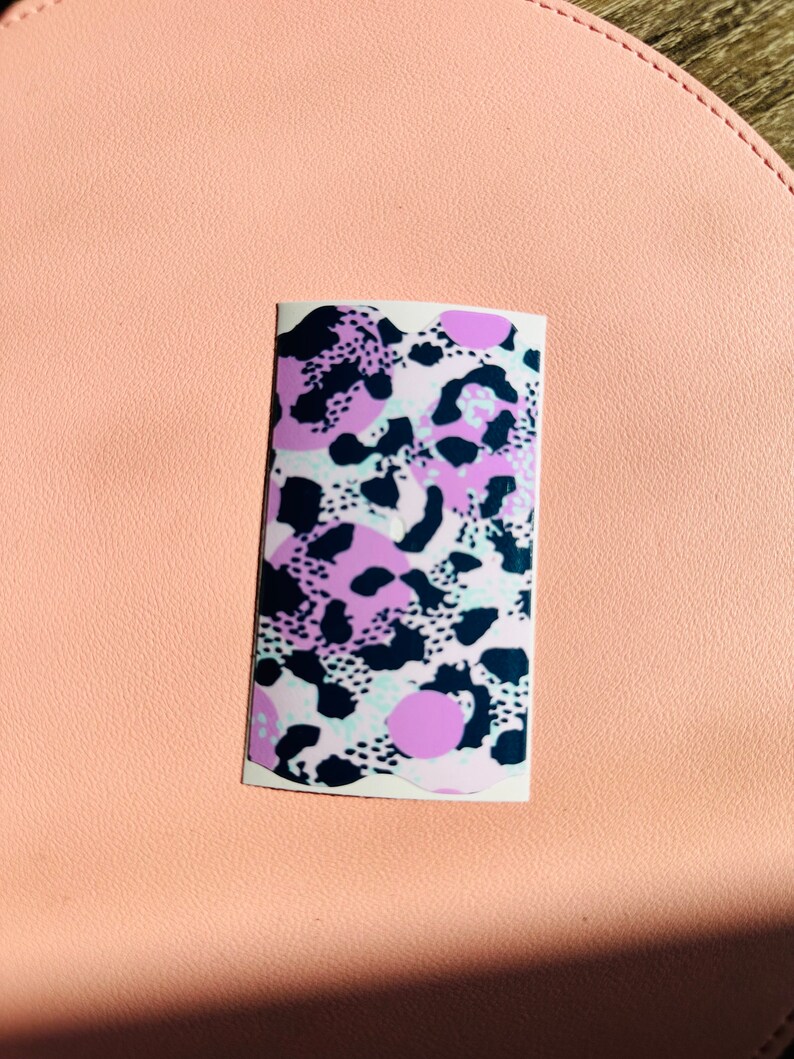 May include: A sticker featuring an abstract animal print design in pink, white and black.