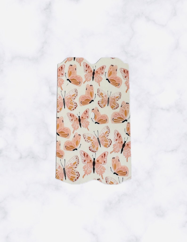 May include: A white tag with a scalloped edge features a repeating pattern of pink and brown butterflies.