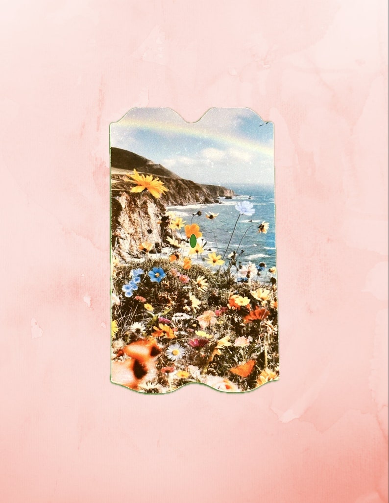 K&ouml;nnte beinhalten: Eine Vintage-Postkarte mit einer malerischen K&uuml;stenlandschaft und einem Regenbogen am Himmel. Die Postkarte ist mit einem Rand aus bunten Blumen verziert.