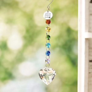 May include: A hanging suncatcher ornament featuring a circular silver charm with the text LOOK FOR ME IN THE RAINBOWS Buddy and a paw print. Below the charm are six faceted crystal beads in rainbow colors, ending in a clear heart-shaped crystal.
