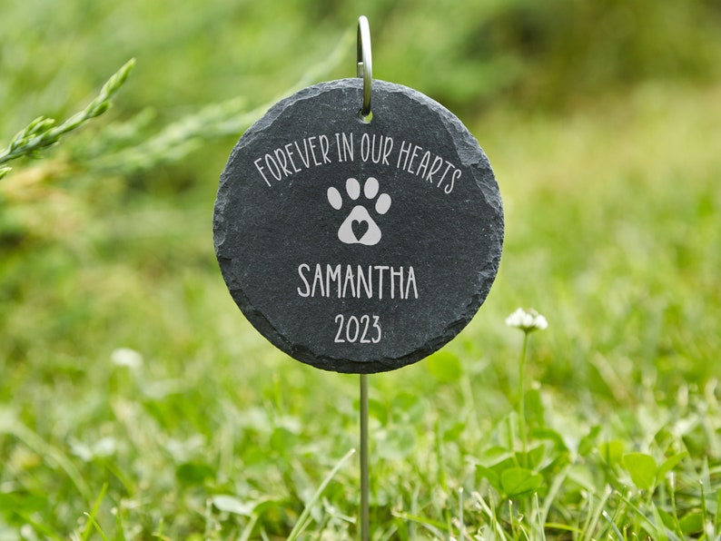 May include: Black slate garden stone memorial with the text "Forever in our hearts" and a paw print with a heart in the center. The name Samantha and the year 2023 are also engraved on the stone.