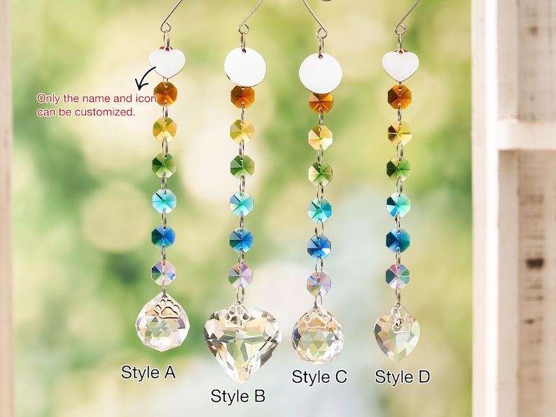 May include: Four hanging crystal suncatchers featuring vertical strands of multi-colored faceted beads in amber, yellow, green, blue, and clear. Each strand ends in a clear crystal shape with a paw print icon. Text reads: Only the name and icon can be customized.