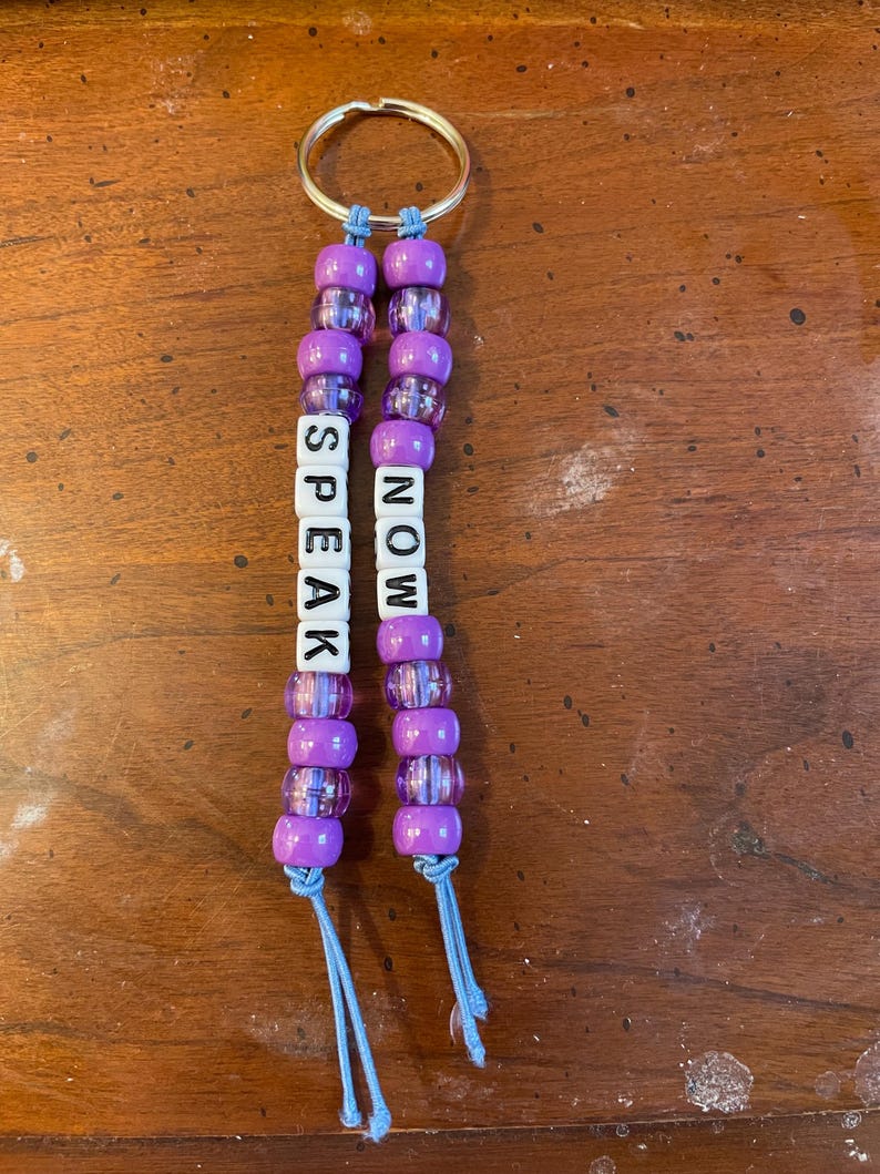 May include: Purple beaded keychain with the words "SPEAK NOW" on it.