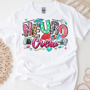 Puede incluir: Camiseta blanca con un dise&ntilde;o gr&aacute;fico colorido que dice "Neuro Crew". El dise&ntilde;o incluye un cerebro, herramientas m&eacute;dicas y otras im&aacute;genes relacionadas con la medicina.