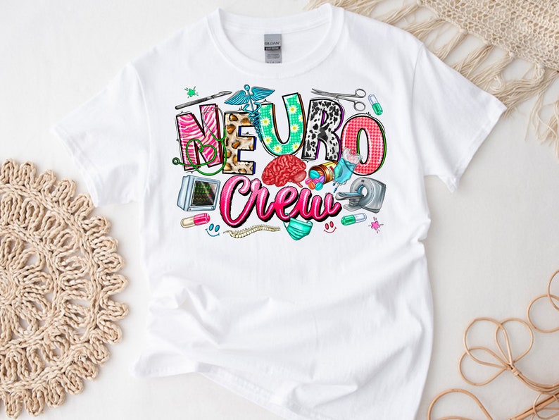 Puede incluir: Camiseta blanca con un dise&ntilde;o gr&aacute;fico colorido que dice "Neuro Crew". El dise&ntilde;o incluye un cerebro, herramientas m&eacute;dicas y otras im&aacute;genes relacionadas con la medicina.