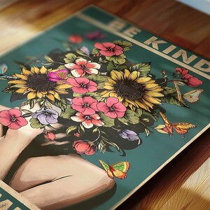 May include: A teal poster with a floral design. It features sunflowers, pink flowers, and butterflies. The words "BE KIND" are printed across the top in a vintage style. The artwork has a soft, artistic feel.