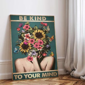 May include: A teal poster with gold lettering that reads "BE KIND TO YOUR MIND." The artwork features a woman with a floral headpiece of sunflowers and pink flowers, with butterflies. The background is teal.