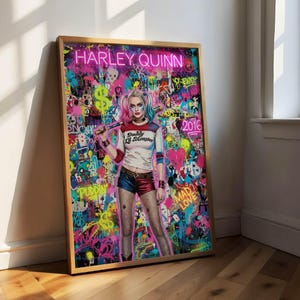Könnte beinhalten: Ein gerahmter Kunstdruck mit Harley Quinn mit rosa und blauen Haaren, die einen Baseballschläger hält. Der Hintergrund ist ein farbenfrohes Graffiti-Design mit den Worten "HARLEY QUINN" in Neonrosa.