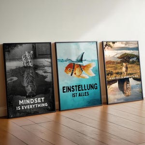 Könnte beinhalten: Drei gerahmte Wandbilder. Das erste zeigt ein Kätzchen mit Tiger-Spiegelung und dem Text "MINDSET IS EVERYTHING". Das zweite zeigt einen Goldfisch mit Haifischflosse und dem Text "EINSTELLUNG IST ALLES". Das dritte zeigt ein Löwenjunges mit Löwen-Spiegelung und dem Text "MINDSET IS EVERYTHING".