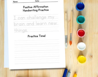 Puede incluir: Una hoja de trabajo imprimible con el texto "Positive Affirmation Handwriting Practice" y la afirmación "Puedo desafiar mi cerebro y aprender cosas nuevas." La hoja de trabajo tiene espacios rayados para practicar la escritura. Hay pinceles, botes de pintura, lápices de colores y rotuladores sobre una superficie de madera.